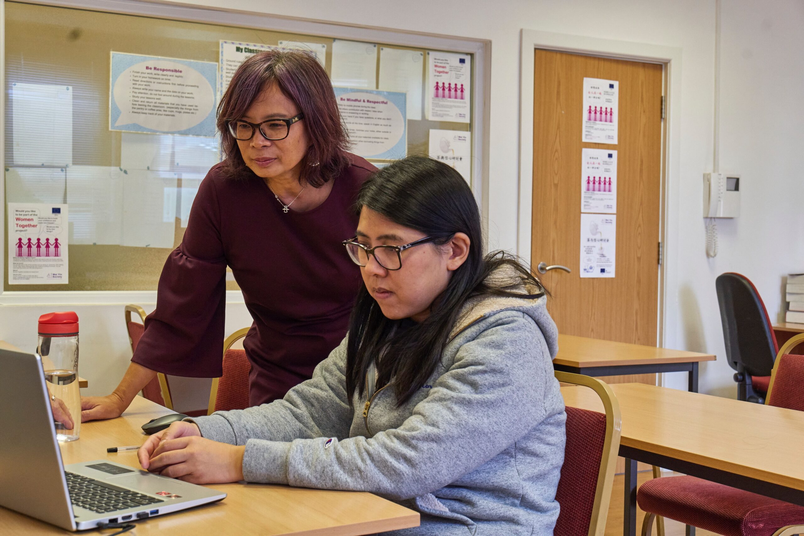 Care worker supporting a young person as they use a laptop